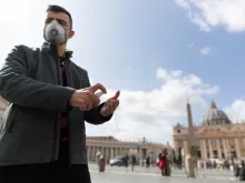 A pilgrim from Russia wears a mask and uses hand sanitizer in front of St. Peter's Basilica at the Vatican March 6, 2020. 