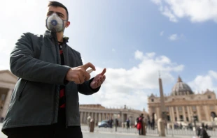 A pilgrim from Russia wears a mask and uses hand sanitizer in front of St. Peter's Basilica at the Vatican March 6, 2020.   Daniel Ibáñez/CNA.
