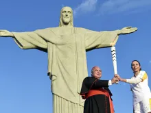 Cardinal Orani Joao Tempesta holds the Olympic torch with former Olympian Isabel Salgado in Rio, Aug. 4, 2016. 