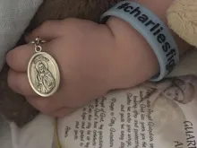 Charlie Gard holds metal of St. Jude. 