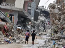 Children amid devastated buildings in Gaza. 