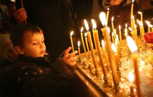 A child lights a candle at Christmas Mass.   haak78, Shutterstock