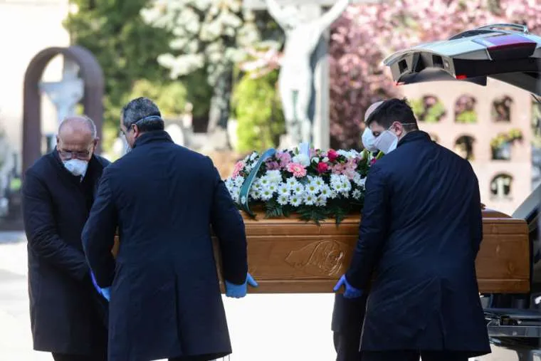 Undertakers wearing face masks carry a coffin in a cemetery in Bergamo, Italy, March 16, 2020. ?w=200&h=150