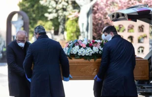 Undertakers wearing face masks carry a coffin in a cemetery in Bergamo, Italy, March 16, 2020.   AFP via Getty Images
