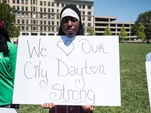 A woman holds a sign at a vigil in honor of those who lost their lives during a shooting in Dayton, Ohio on August 04, 2019. 