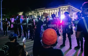 Demonstrators sit in the street, in front of law enforcement, Aug. 25, 2020 in Kenosha, Wis. A third night of civil unrest occurred after the shooting of Jacob Blake.