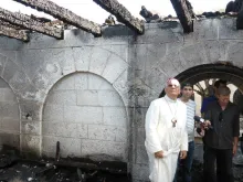 Fouad Twal, then-Patriarch of Jerusalem, inspects damage to the Church of the Multiplication from the June 18, 2015 arson attack. 