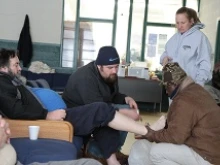 Emmanuel House guest John Compas tends to Joseph Follett, a fellow homeless guest at the diocesan emergency shelter. 