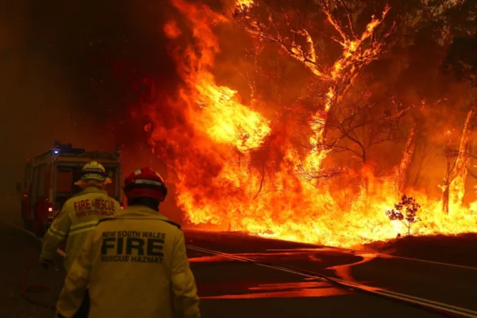 Fire and Rescue personal run to move their truck as a bushfire burns next to a major road and homes near Bilpin on December 19 2019 By SS studio photography Shutterstock