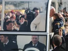 Fr. Fabian Baez (back left) was invited to ride in the back of the popemobile after being spotted by Pope Francis in St. Peter's Square Jan. 8, 2014. 