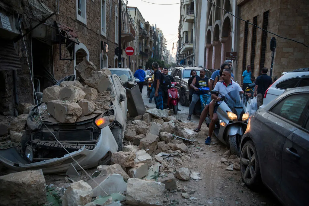 People ride past a car destroyed after a building wall collapsed after a large explosion on August 4, 2020 in Beirut, Lebanon. ?w=200&h=150