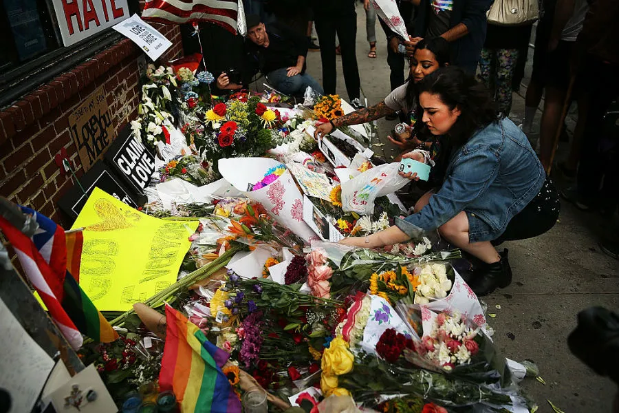 A girl places flowers at a vigil following the June 12, 2016 mass shooting a gay night club in Orlando. ?w=200&h=150