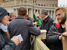 Msgr Guido Marini, Papal MC, assists volunteers in distributing copies of the Gospels at the Holy Father's Angelus address, March 22, 2015. 