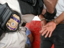 Immigrations and Customs Enforcement (ICE) officer escorting a man in handcuffs
