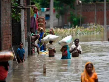 Indians wade along a flooded street carrying their belongings following heavy monsoon rains at Sitamarhi district in Bihar state, July 17, 2019. 
