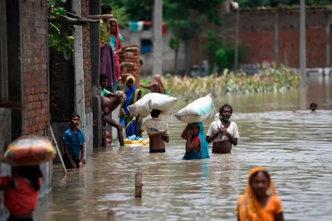 Indians wade along a flooded street carrying their belongings following heavy monsoon rains at Sitamarhi district in Bihar state July 17 2019 Credit Sachin Kumar AFP Get
