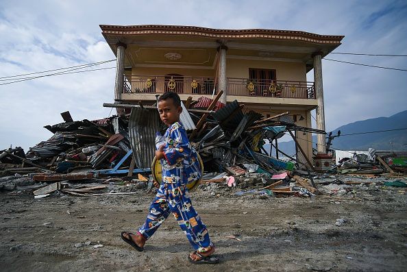 A boy walks in front of tsunami debris in Palu, Indonesia on Oct. 4, 2018, after a Sept. 28 earthquake and tsunami. ?w=200&h=150