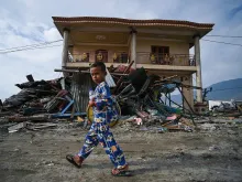 A boy walks in front of tsunami debris in Palu, Indonesia on Oct. 4, 2018, after a Sept. 28 earthquake and tsunami. 