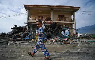 A boy walks in front of tsunami debris in Palu, Indonesia on Oct. 4, 2018, after a Sept. 28 earthquake and tsunami.   AFP/Getty Images.