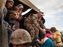 Jordanian troops and UNHCR officials help bring Syrian refugees to Jordan's Zaatari refugee camp. 