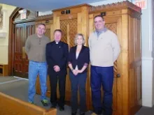 (L-R) Timothy Conlon, Fr. Janusz Kukulka, Lisa Knott and her husband Patrick, stand in front of the refurbished confessional. 