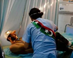 A rebel fighter grimaces as he receives medical attention for a gun wound to the shoulder at Tripoli Central Hospital on August 25, 2011 in Tripoli, Libya. ?w=200&h=150