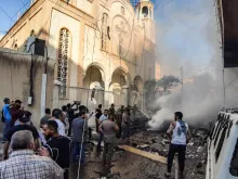 People extinguish a fire at the scene of a car bomb explosion outside the Syriac Orthodox Church of the Virgin Mary in Qamishli, Syria, July 11, 2019. 