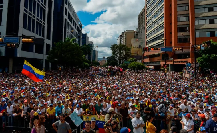 La gente escucha al jefe de la Asamblea Nacional de Venezuela, Juan Guaido (fuera del marco), durante un mitin de la oposición contra Nicolás Maduro en Caracas, 23 de enero de 2019. Crédito: Federico Parra / AFP / Getty Images.