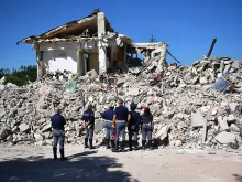 Police officers view the remains of a building that was destroyed during an earthquake, on August 25, 2016 in Amatrice, Italy. 