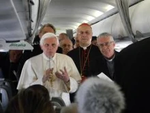 Pope Benedict XVI speaks to reporters on the papal flight to Scotland