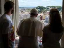 Pope Francis with two World Youth Day volunteers looks over St. Peter's Square July 26, 2015. 