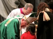 Pope Francis leans down to a girl at Feb. 23 Sunday Mass at St. Peter's Basilica, 