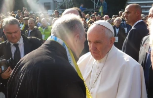 Pope Francis greets a local priest during his visit to the