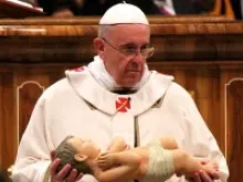 Pope Francis holds a statue of the Christ child for the nativity scene on December 24, 2013. 