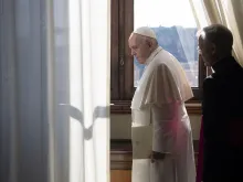 Pope Francis looks out a window of the apostolic palace March 18, 2020. 