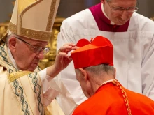 Pope Francis places a red biretta on the head of a new cardinal during a consistory held in St. Peter's Basilica, June 28, 2018. 