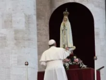 Pope Francis touches a statue of Our Lady of Fatima at an Oct. 12 vigil in St. Peter's Square. 