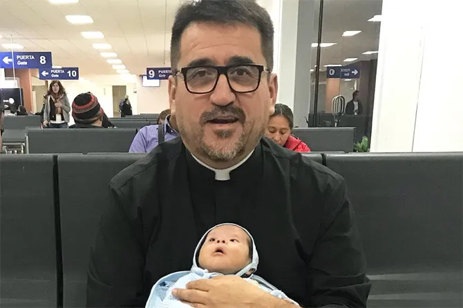 Priest holding baby CNA