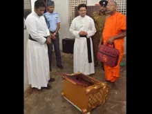 Priests, a Buddhist monk and police inspect a desecrated tabernacle. (
