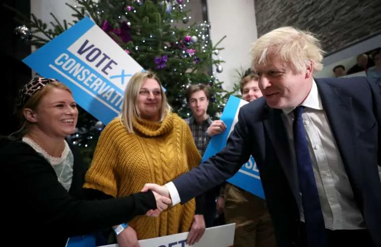 Prime Minister Boris Johnson greets a woman as he arrives to attend a campaign rally event Dec. 2, 2019 in Colchester, England. ?w=200&h=150