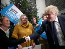 Prime Minister Boris Johnson greets a woman as he arrives to attend a campaign rally event Dec. 2, 2019 in Colchester, England. 