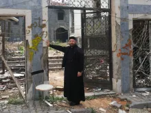A priest stands before the ruins of St. Mary's Syriac Orthodox parish in Homs. 