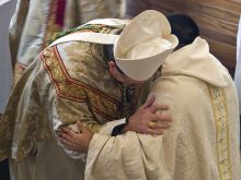 A bishop and a priest exchange the sign of peace during Mass. 