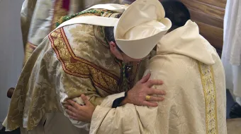 A bishop and a priest exchange the sign of peace during Mass.