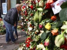 People look through a gate of flowers where behind it work continues at the scene of the bomb explosion in Oslo, Norway. 