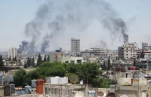 Smoke billows skyward as homes and buildings are shelled June 9, 2012 in the city of Homs, Syria.   UN Photo-David Manyua.