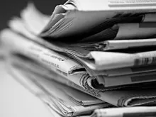 Black and white added stack of newspapers. 