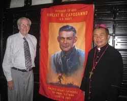 Ted Bronson and Bishop Joseph Tri stand in front of a banner of Servant of God Fr. Vincent Capodanno in Vietnam, June 2013. ?w=200&h=150