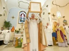Father John Baker holds up the letter bestowing the designation of Basilica on St. Mary Star of the Sea Catholic Church in Key West, Fla.