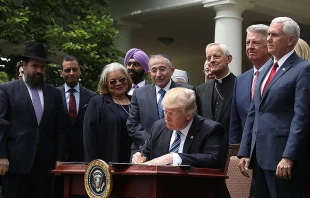 U.S. President Donald Trump flanked by religious leaders as he signs an executive order on religious freedom May 4, 2017.